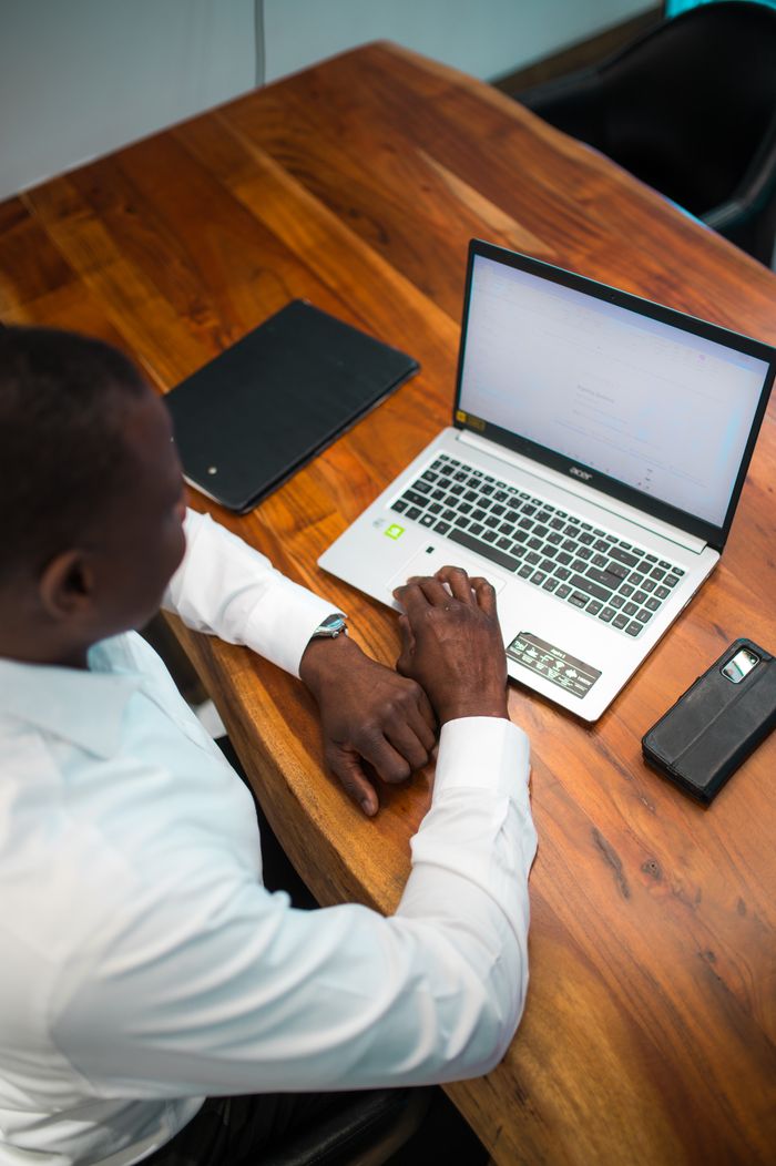 why-choose-us Businessman using a laptop at his wooden desk in an office environment.