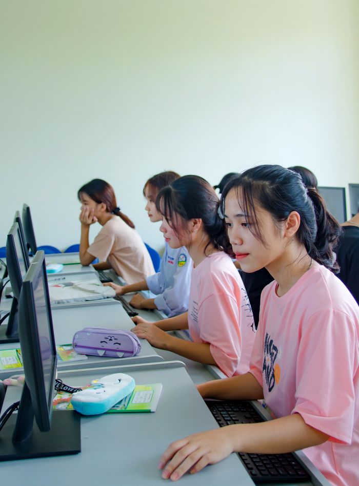 creative-approach-img A group of young students focused on computer tasks in a modern classroom setting.