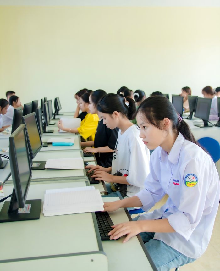 portfolio-05 Students focus on computer tasks in a classroom setting, emphasizing education and technology skills.