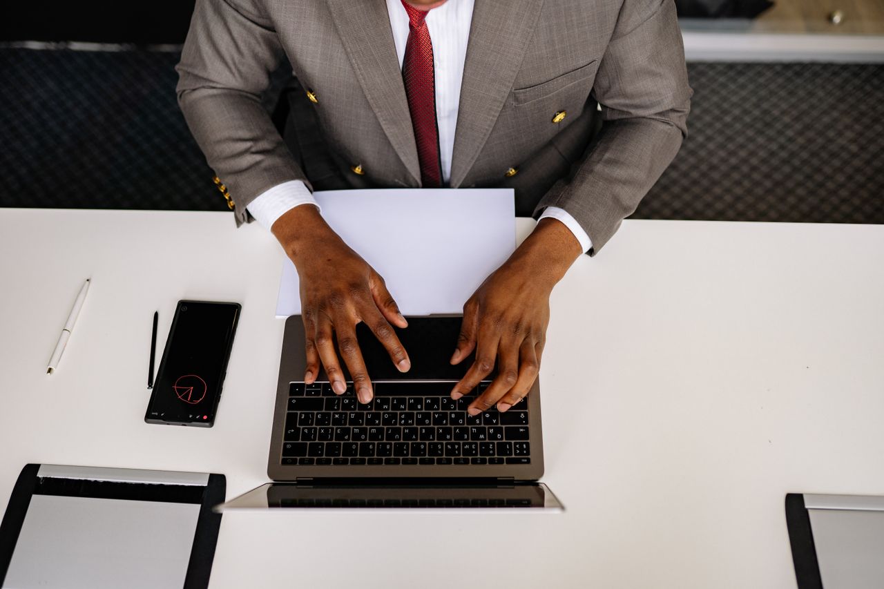 Overhead view of a businessman in a suit typing on a laptop in an office setting.